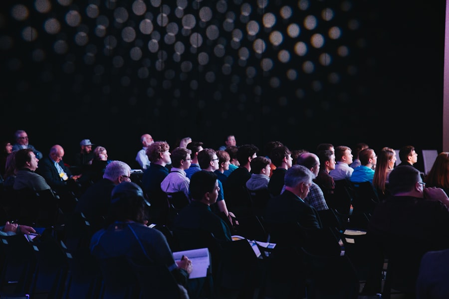 Attendees seated in a darkened conference hall during a presentation